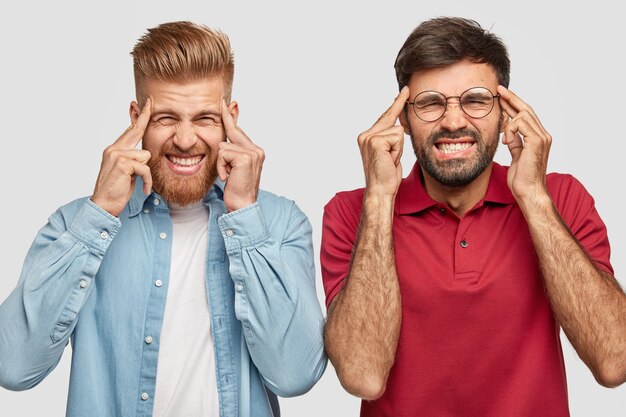 frustrated bearded brothers posing against the white wall