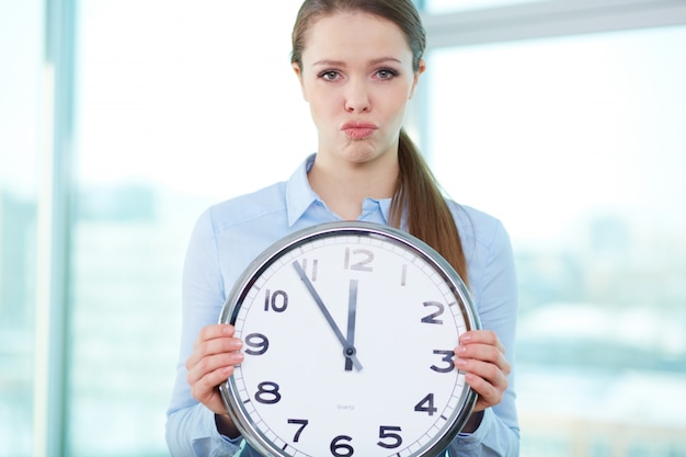 Free photo frustrated businesswoman holding a big clock