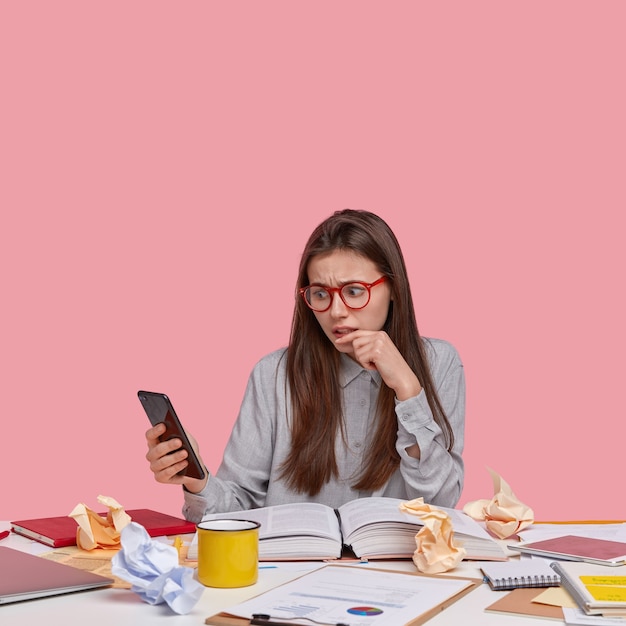 Frustrated displeased woman reads negative news on internet website, connected to wifi, works on developing new strategy in business