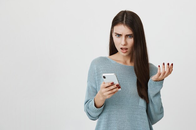 Frustrated shocked woman stare at mobile phone upset