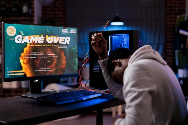 Free photo frustrated streamer losing online shooter video games play competition on computer with neon lights. male gamer streaming action gameplay and feeling sad about lost shooting championship.