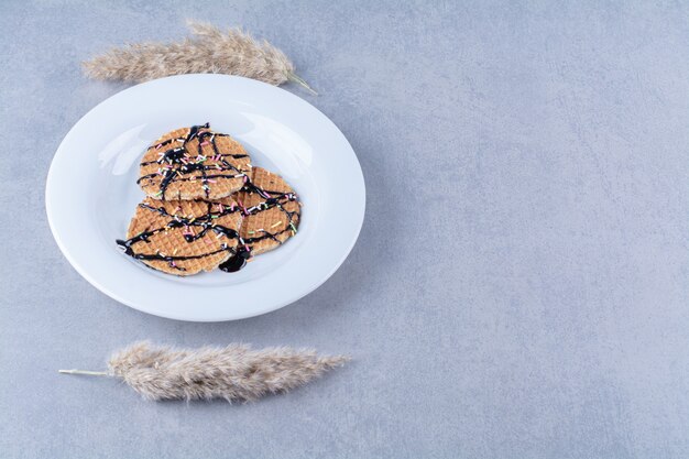 A frying pan of round ruddy waffle with sprinkles and cream . 