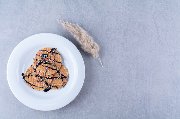 A frying pan of round ruddy waffle with sprinkles and cream . 