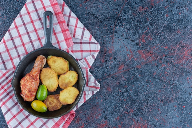 A frying pan with chicken meat and vegetables