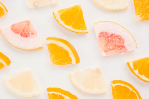 Full frame of lemon; orange and grapefruit slices on white backdrop