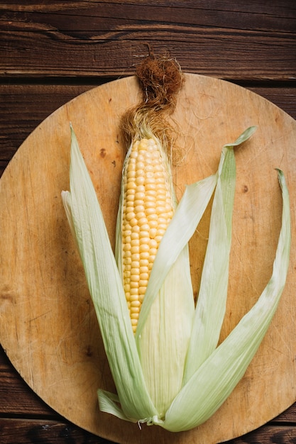 Full grown corn with leaves on a cutting board