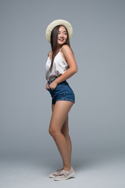 Full height asian girl in straw hat on gray background