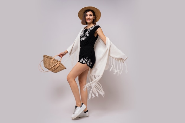 Free Photo full length glad woman with short hairstyle in stylish boho summer outfit. straw hat and bag.