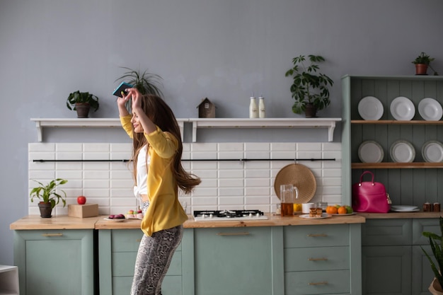 Free Photo full length of gorgeous brunette in fashionable clothes and heels dancing in the kitchen feeling happy in the morning modern interior