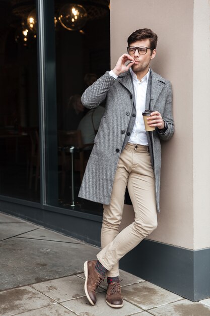 Full length image of businessman in eyeglasses and coat