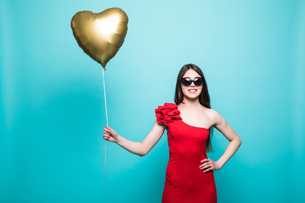 Free Photo full-length image of gorgeous woman in fancy red outfit posing with heart shape ballon, isolated over green wall