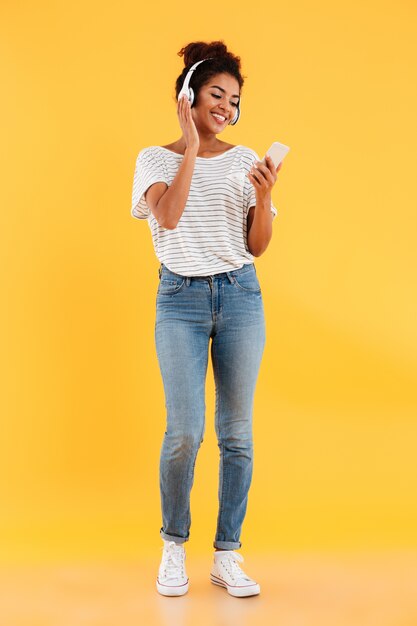 Full length image of happy african woman listening music