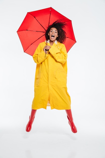 Free photo full length image of happy screaming african woman in raincoat