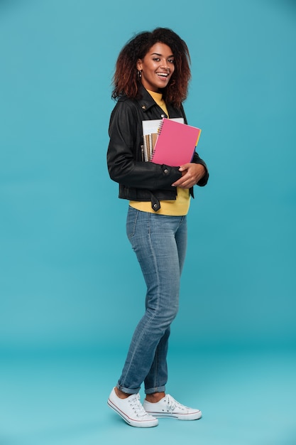 Full length image of smiling african woman in leather jacket