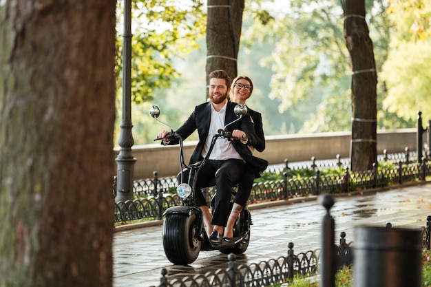 Full length image of young elegant couple rides on motorbike