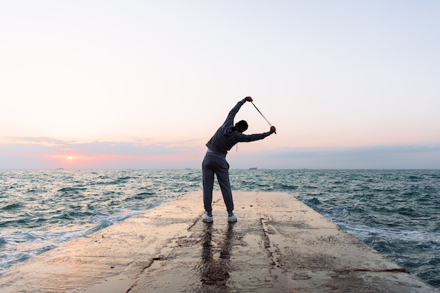 Free photo full length photo of sportsman practicing exercises, stretching with skipping rope