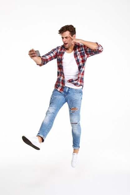 Full length portrait of a casual man taking a selfie