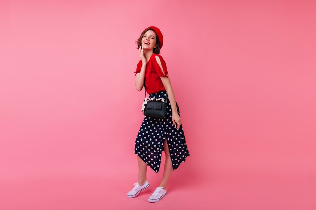 Full-length portrait of enthusiastic french lady smiling. Debonair short-haired woman in long skirt standing in confident pose.