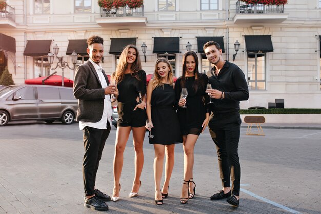 Full-length portrait of fashionable female model in confident pose standing between friends