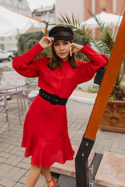 Full-length portrait of fashionable Parisian woman in silk dress with black leather belt. Girl with long eyelashes posing attractively