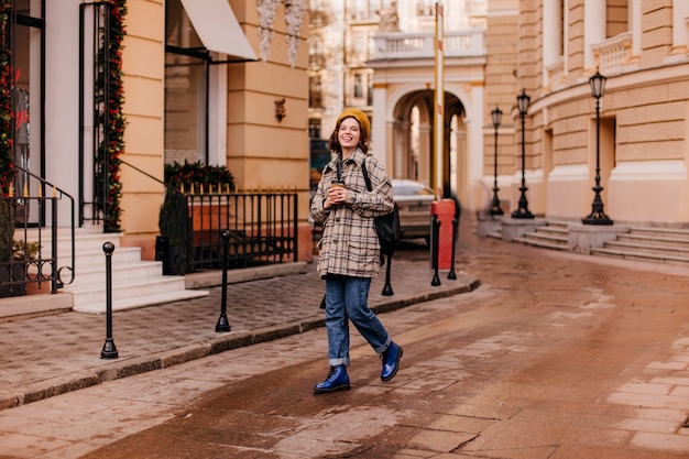 Free Photo full-length portrait of female student walking in city center. woman in blue shoes