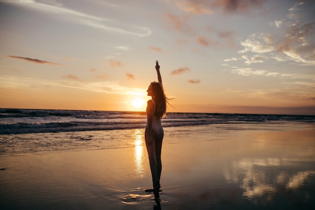 Free photo full-length portrait from back of girl looking at sea sunset.