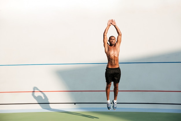 Free photo full length portrait of a half naked african fitness man jumping