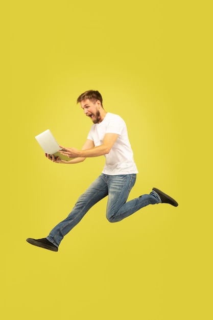 Full length portrait of happy jumping man isolated on yellow