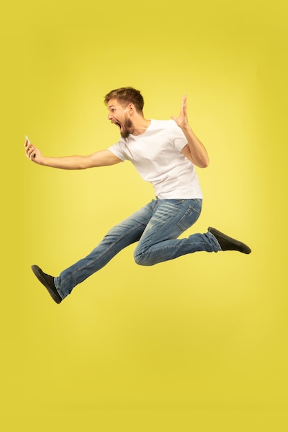 Free Photo full length portrait of happy jumping man isolated on yellow