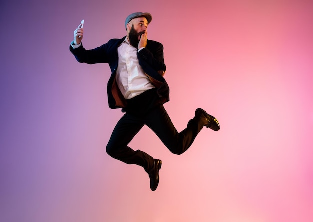 Full length portrait of happy jumping man in neon gradient light