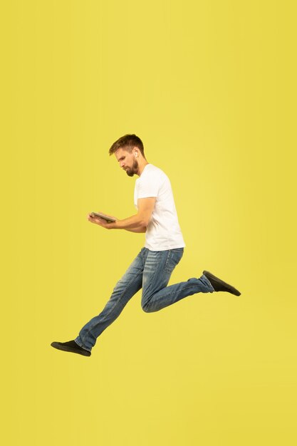 Full length portrait of happy jumping man on yellow wall