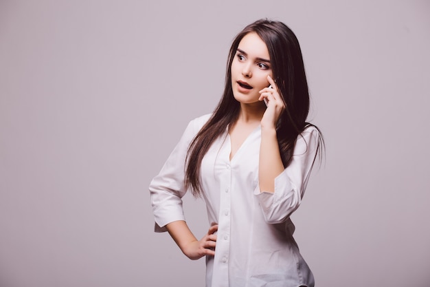 Full length portrait of a happy young woman talking on the phone isolated on a white background