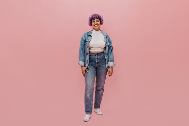 Free photo full-length portrait of joyful woman with short purple hair in denim suit, white sneakers and light top smiling