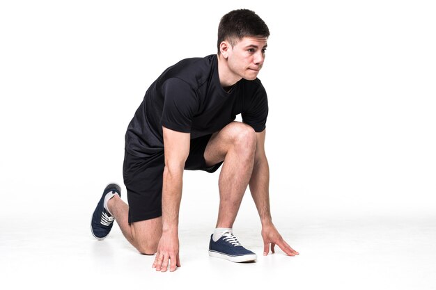 Full length portrait of a male athlete ready to run isolated on white 