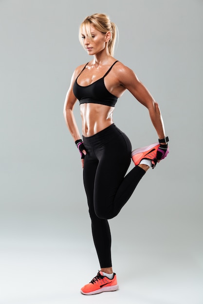 Full length portrait of a pretty sportswoman doing stretching exercises