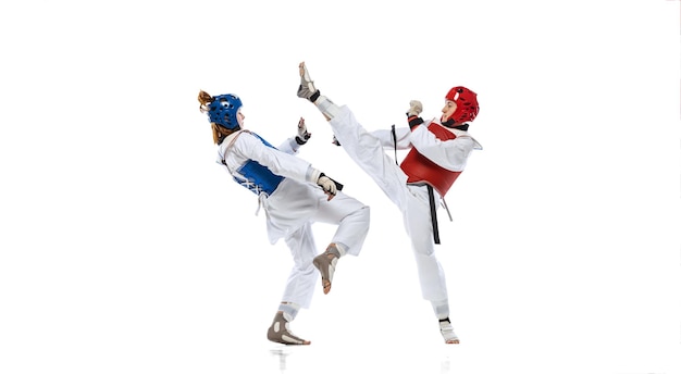 Full-length portrait of two professional taekwondo feale athletes fighting isolated over white background