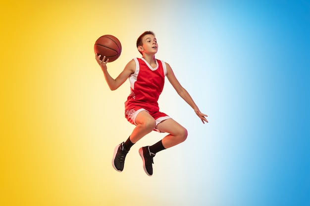 Full length portrait of a young basketball player with ball on gradient background