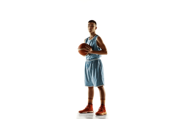 Full length portrait of young basketball player with a ball isolated on white studio background. Teenager confident posing with ball. Concept of sport, movement, healthy lifestyle, ad, action, motion.