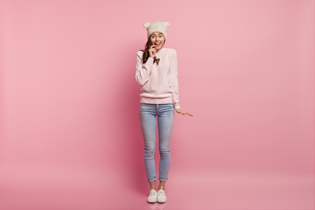 Full length shot of pleasant looking charming woman dressed in casual white jumper