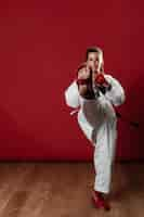 Free photo full length shot of a woman with black belt and kimono practicing karate