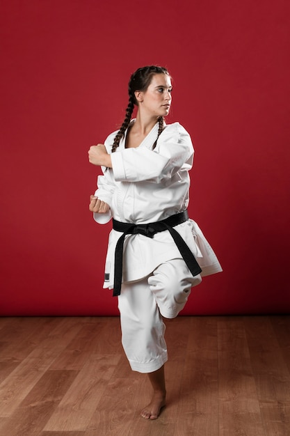 Free photo full length shot of a woman with black belt and kimono practicing karate