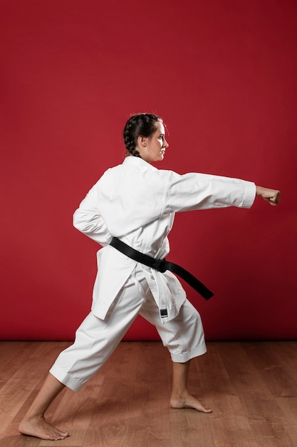 Free photo full length shot of a woman with black belt and kimono practicing karate