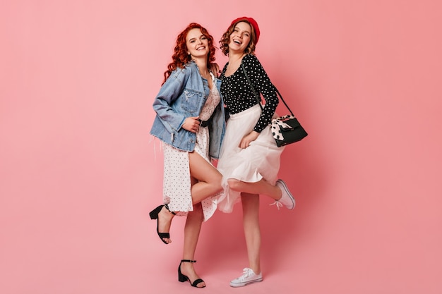 Free photo full length view of graceful girls dancing with smile. studio shot of friends in casual attire.