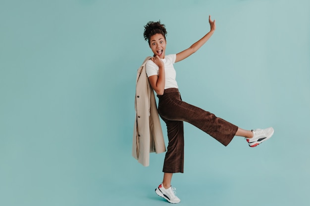 Full length view of wonderful woman dancing on turquoise wall