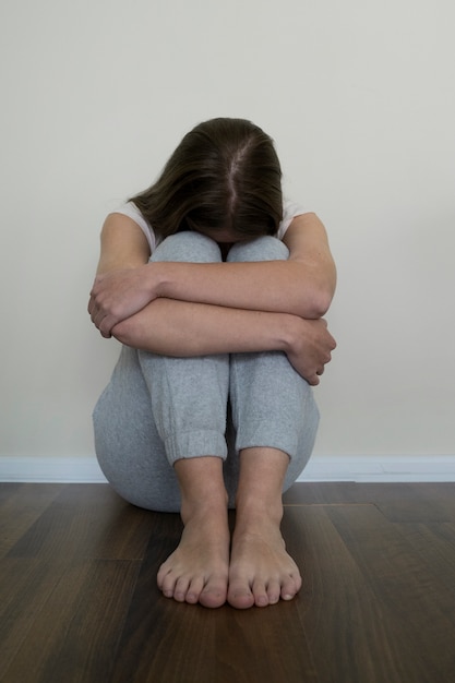 Full shot anxious woman sitting on floor