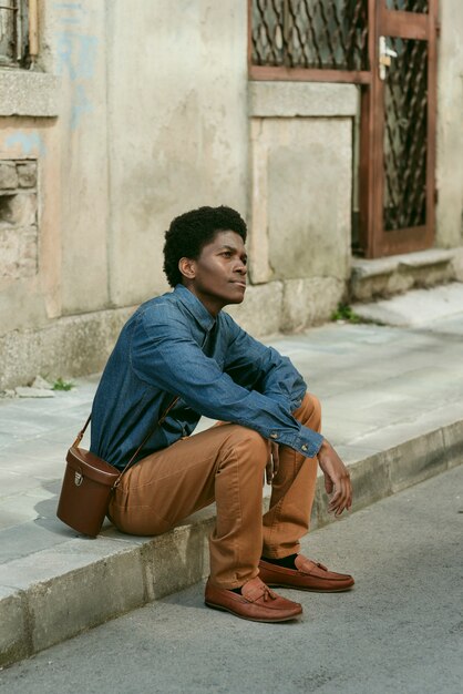 Full shot black man sitting outdoors