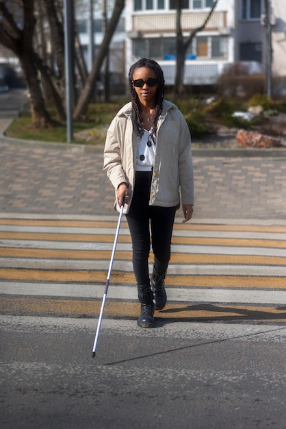 Full shot blind woman on crosswalk with cane