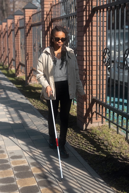 Free photo full shot blind woman walking with white cane