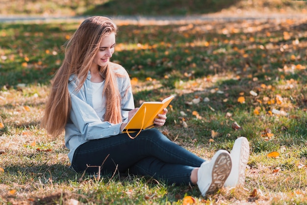 Free Photo full shot blonde woman writing in a notebook