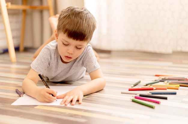 Full shot boy on floor drawing